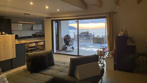 Ein modernes Wohnzimmer mit Sofa, Essbereich und Meerblick.