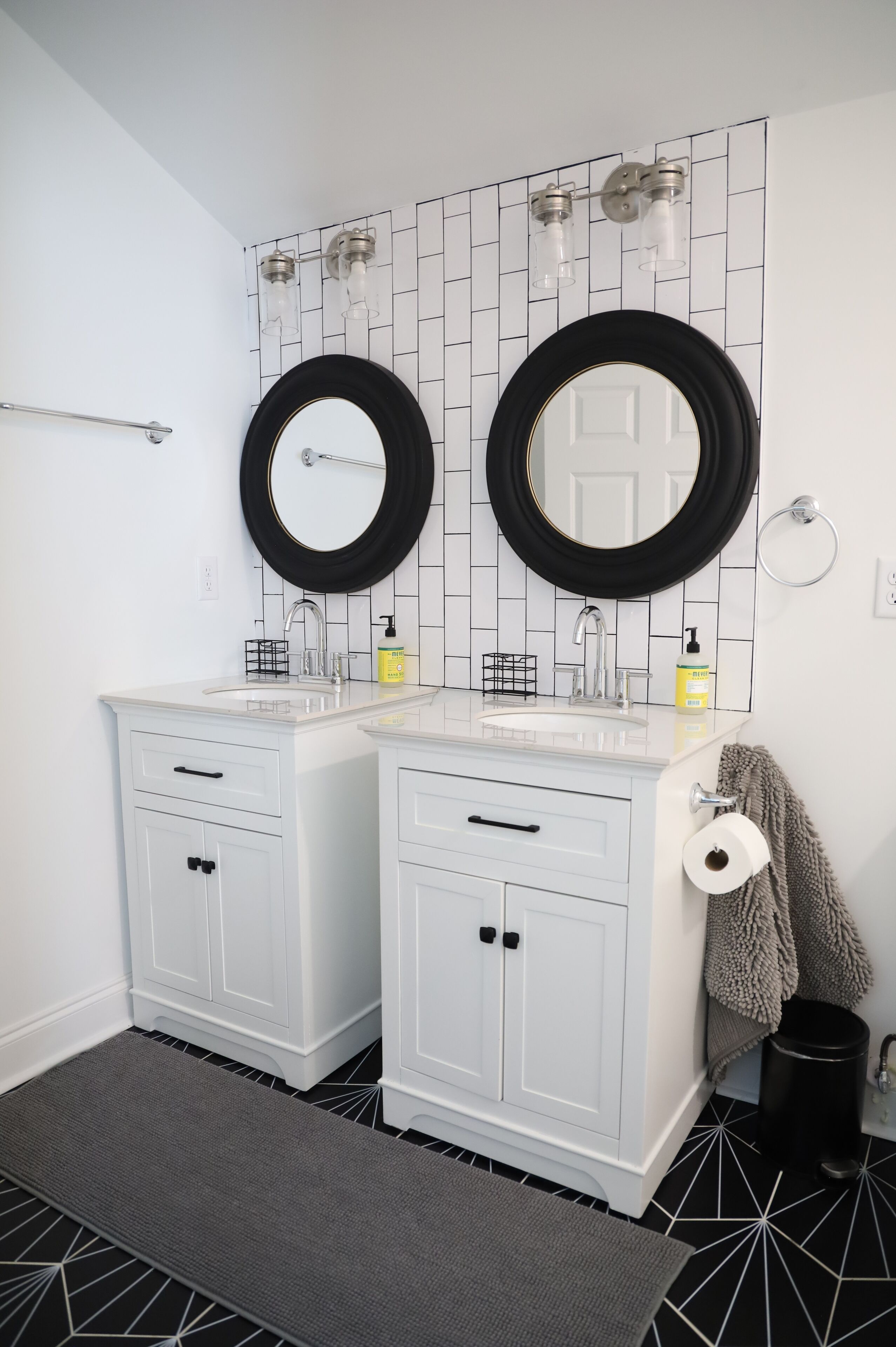 A bathroom with two sinks, a mirror, and a towel rack.