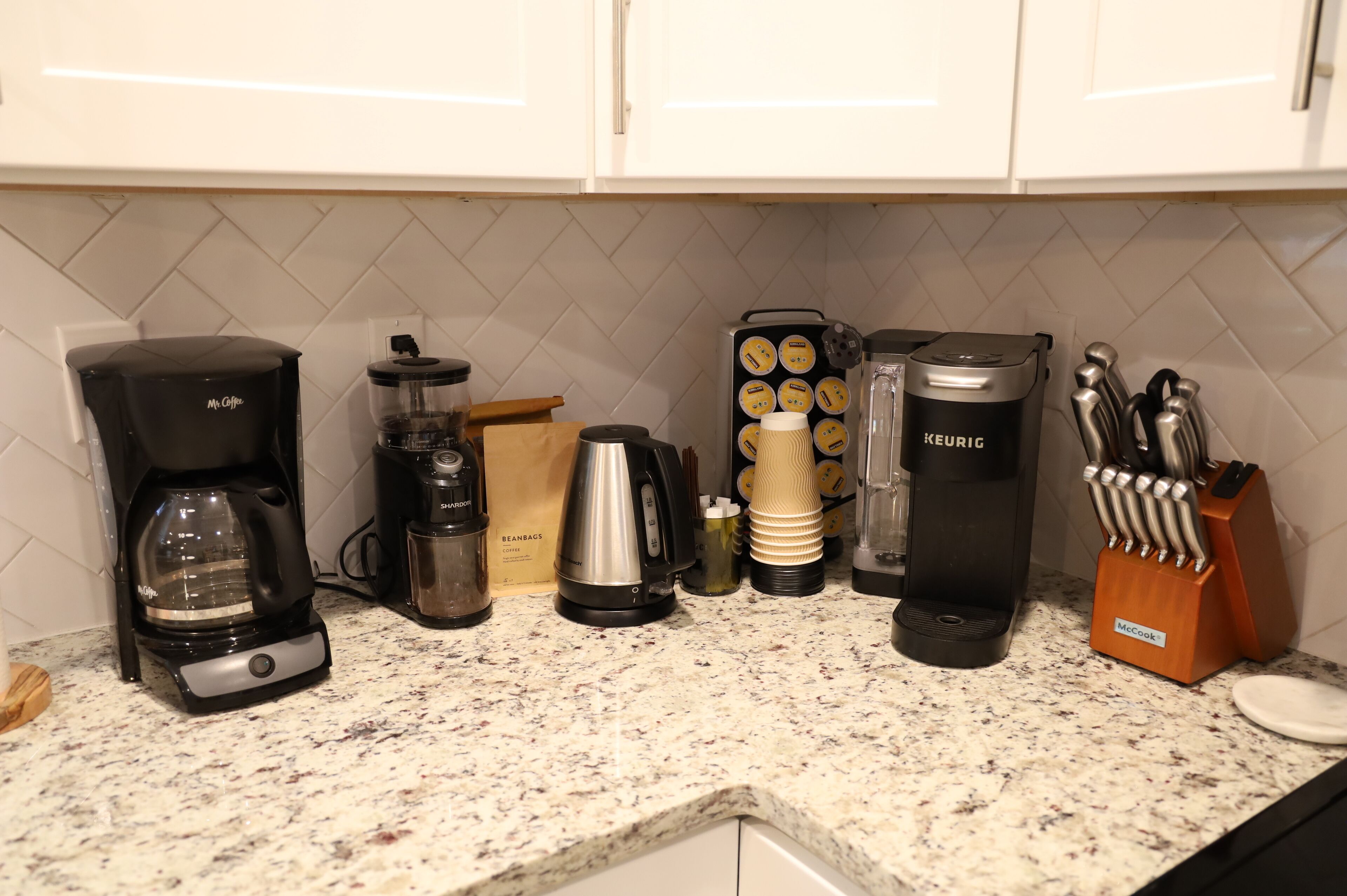 Een aanrecht met diverse apparaten, waaronder een koffiezetapparaat, een blender en een Keurig koffieapparaat.