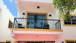 A two-story building with a balcony on the upper floor, a covered entrance, and a staircase leading to the entrance.