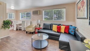 Un salon moderne comprenant un canapé, des fauteuils, une table basse en verre et un coin repas avec une table et des chaises.