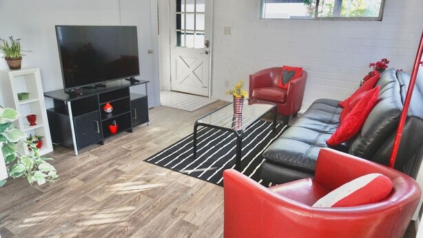 Un salon moderne avec un téléviseur à écran plat, un canapé rouge, un fauteuil rouge et un tapis rayé noir et blanc.