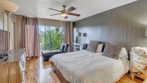 Un dormitorio con una cama grande, un escritorio, una silla y un ventilador de techo.