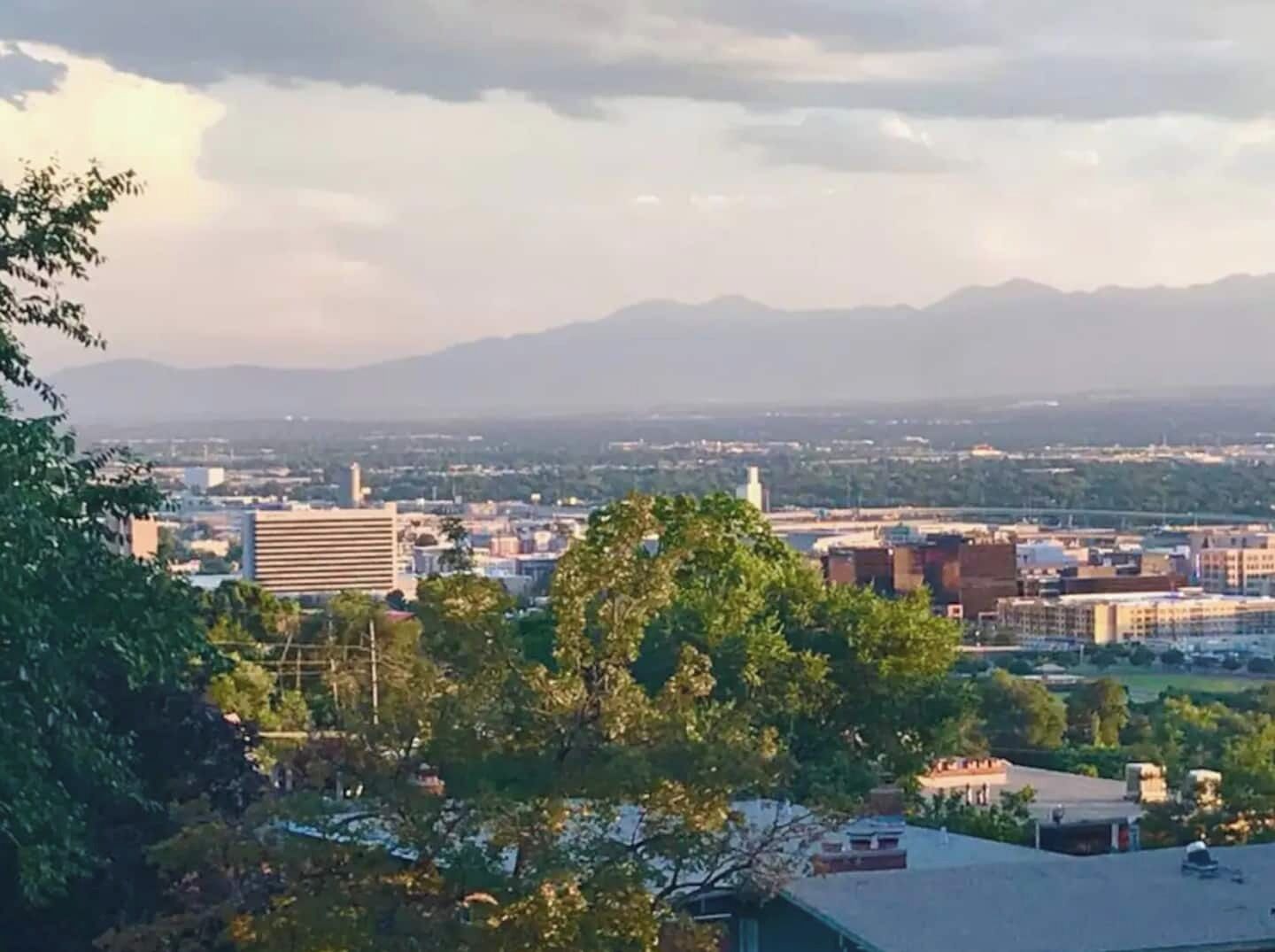 A cityscape with buildings, trees, and mountains in the distance.