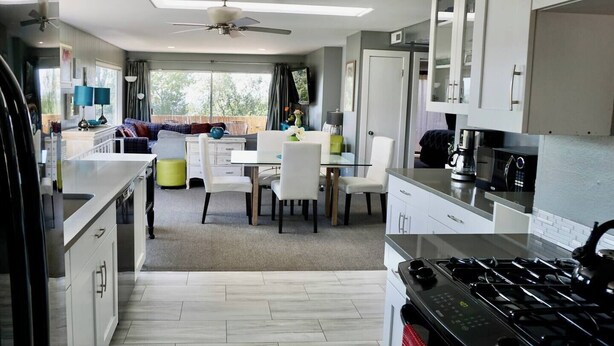 A modern kitchen with a dining area, white cabinetry, and a large window providing natural light. - “Stunning Views!” Luxury 4 Bedroom, 2 Bathroom Vacation Duplex in Downtown Salt Lake Capitol Hill (Salt Lake City)