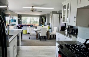 A modern kitchen with a dining area, white cabinetry, and a large window providing natural light. - “Stunning Views!” Luxury 4 Bedroom, 2 Bathroom Vacation Duplex in Downtown Salt Lake Capitol Hill (Salt Lake City)