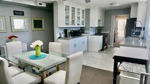A modern kitchen with white cabinets, a dining table with chairs, and a glass-top table with a vase of flowers. - “Stunning Views!” Luxury 4 Bedroom, 2 Bathroom Vacation Duplex in Downtown Salt Lake Capitol Hill (Salt Lake City)
