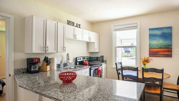 A kitchen with white cabinets, a granite countertop, a red woven basket, and a painting on the wall. - Heritage House -Great Location, Skiing, Walk to Restaurants, Sports Fields, Train.  Large rooms (Heber City)