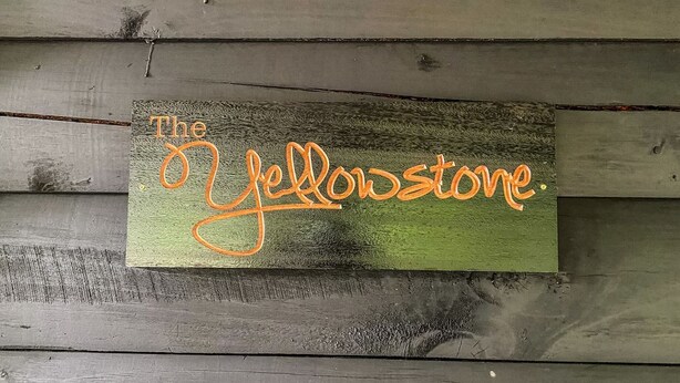 Een houten bord met de tekst 'The Yellowstone' in oranje.