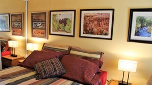 A hotel room with a bed, a nightstand, a chair, and framed pictures on the wall. - for animal lovers - cute, little Bunkhouse attached to the horse barn (Sonoita)