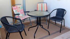 A small outdoor seating area with a round glass table and three chairs, one with a floral cushion. - for animal lovers - cute, little Bunkhouse attached to the horse barn (Sonoita)