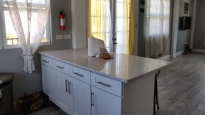 Une cuisine moderne avec des armoires blanches, un plan de travail et un extincteur fixé au mur.