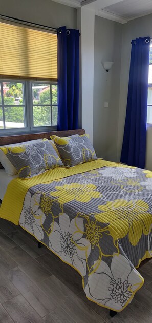 A bedroom with a bed, window, curtains, and a lamp.