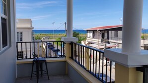Un balcon avec vue sur l’océan et les bâtiments environnants.