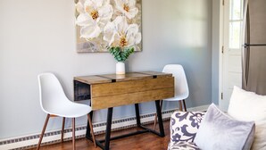 A room with a wooden desk, two white chairs, a vase with flowers, and a patterned cushion on a sofa. - Nona's Cottage-Waynesboro/Shenandoah Valley, VA (Waynesboro)