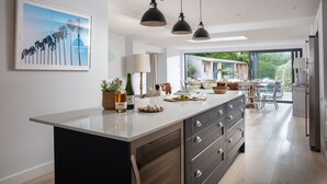 Una cocina moderna con una isla grande, iluminación colgante y vistas al patio exterior.