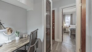 Un couloir avec un bureau en bois, un miroir et une plante en pot.