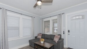 Un salon avec un canapé gris, une table basse en bois et un ventilateur de plafond.