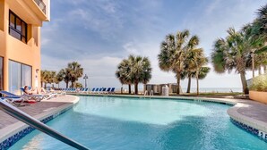 A pool area with lounge chairs and palm trees, overlooking a body of water. - Paradise @ Oceanfront Suite/Dogs OK! (Myrtle Beach)