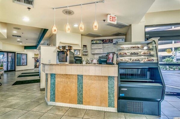 A bakery counter with a cash register, a menu board, and a display case with baked goods.