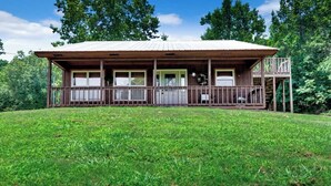 Une cabane en bois avec un porche, un garage et une petite terrasse.