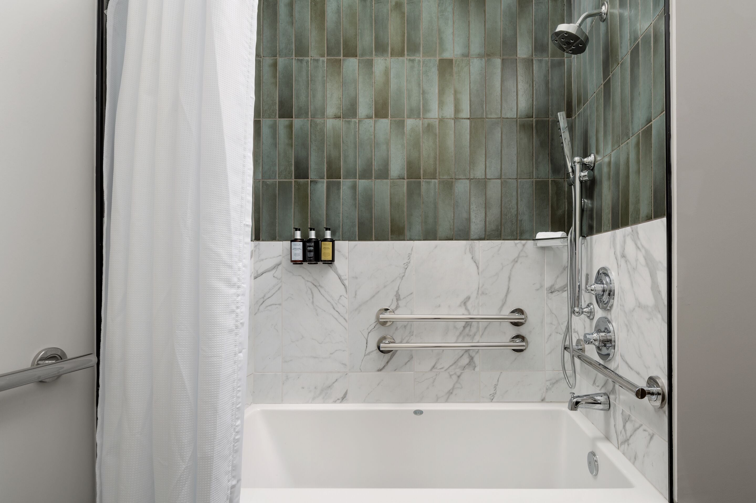 Un bagno moderno con vasca, doccia e mancorrenti.