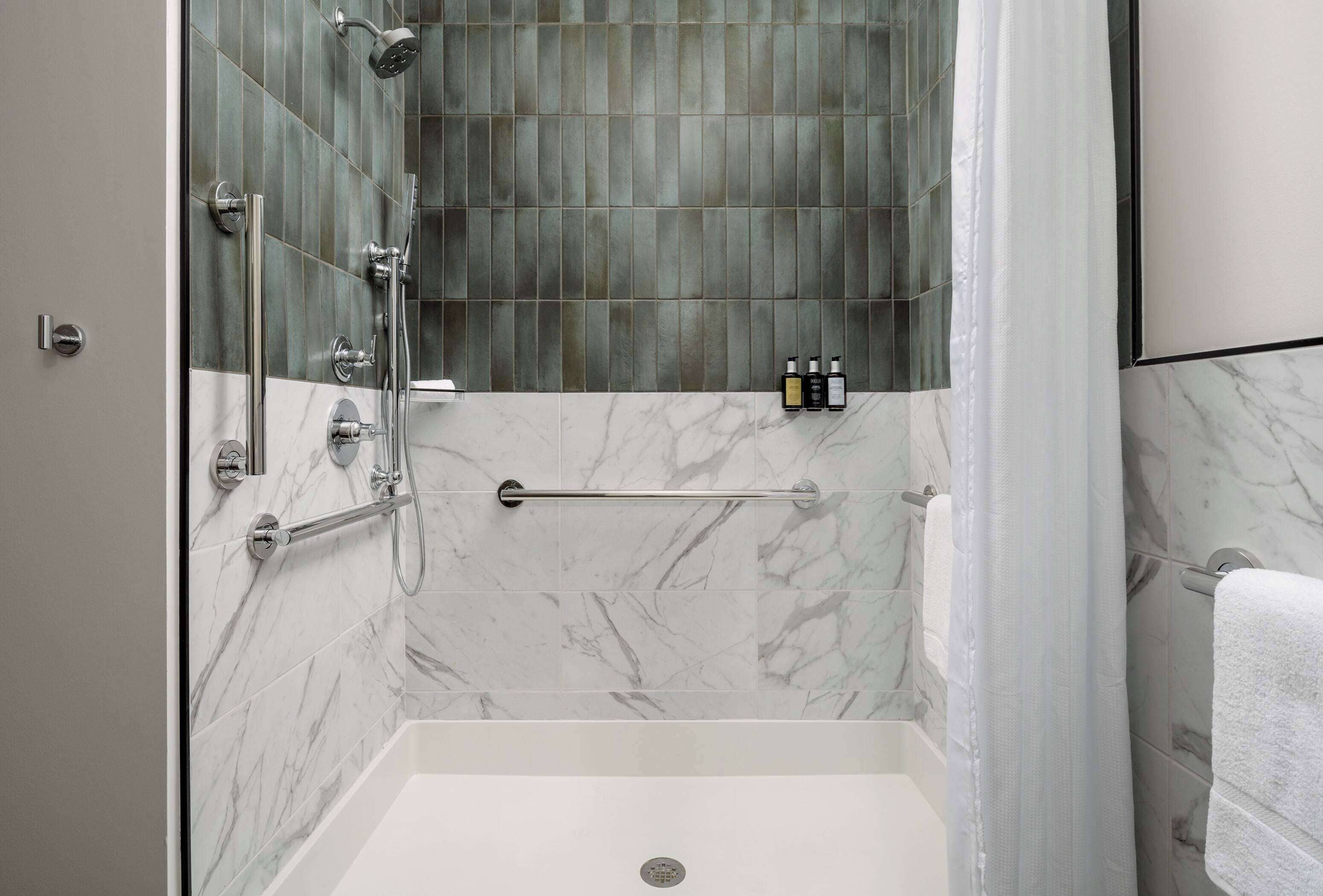 Une douche moderne avec une porte en verre et un pommeau de douche à main.