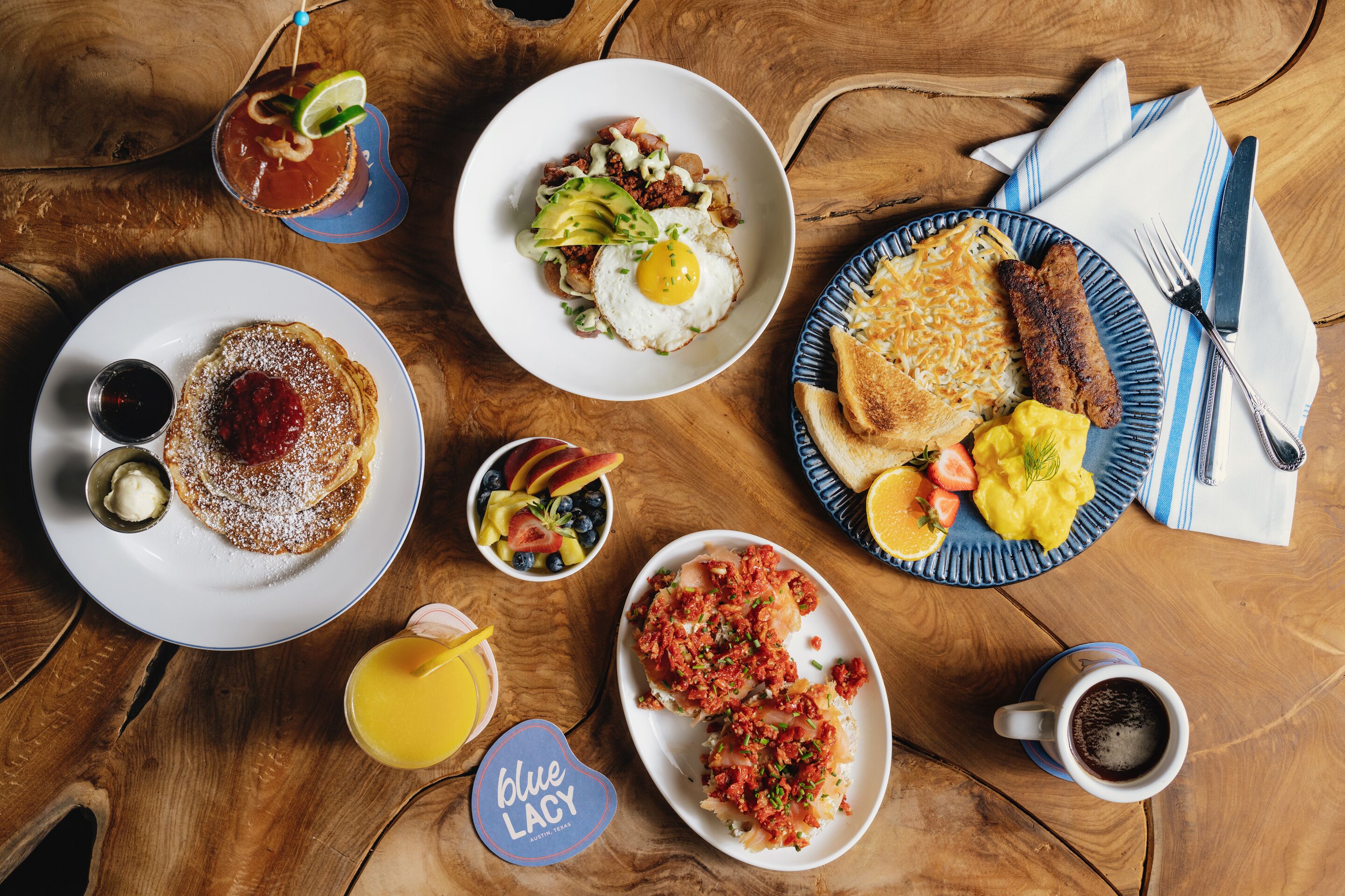 A wooden table with various breakfast dishes, including pancakes, eggs, and toast.