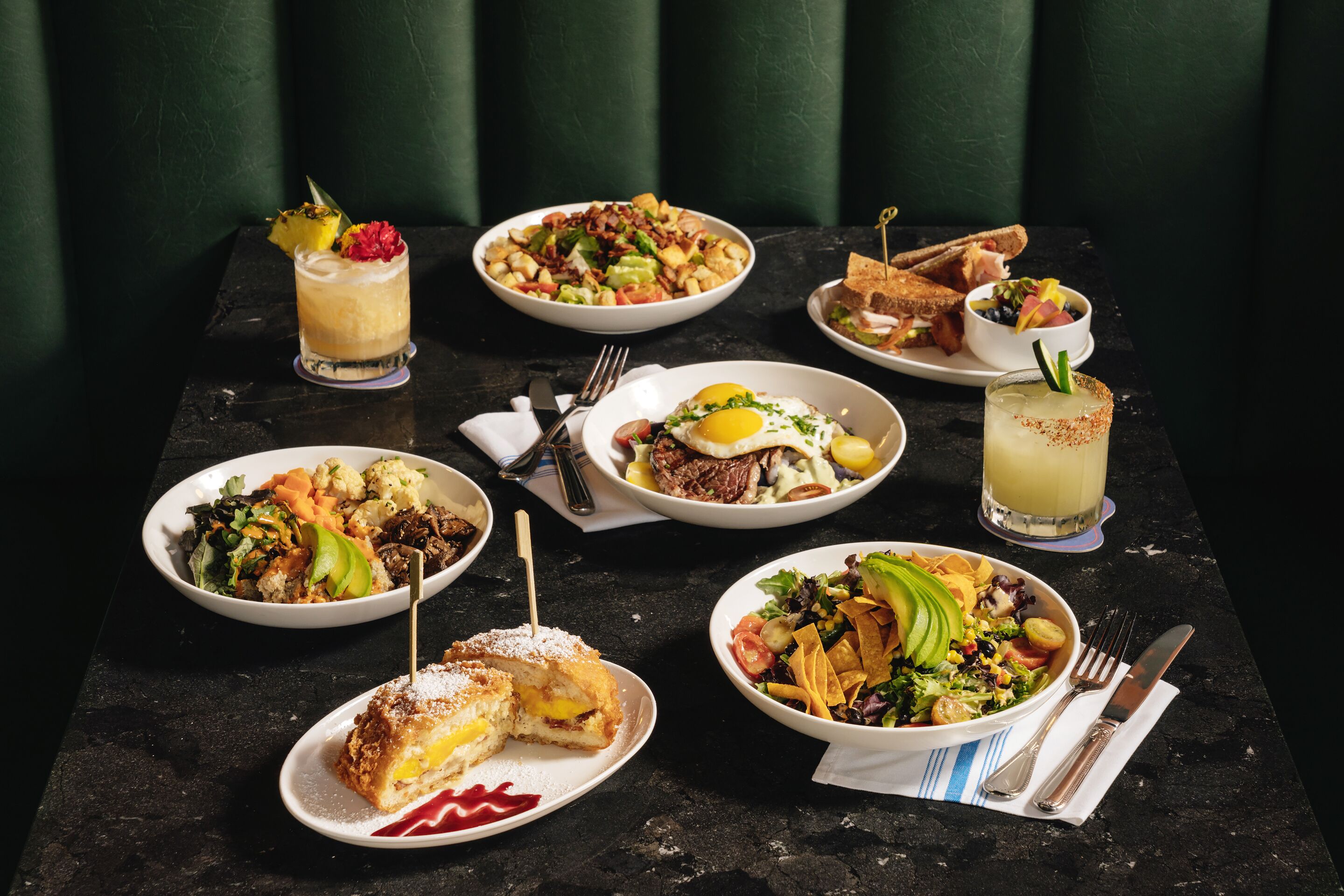 A variety of dishes on a table, including a salad, a sandwich, and a dessert.