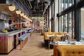 A modern cafe with a bar area, wooden flooring, and large windows. - Origin Austin, A Wyndham Hotel (Austin)
