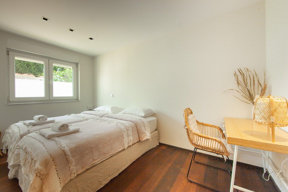 Een slaapkamer met een bed, een stoel, een tafel en een raam.