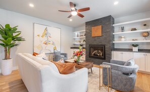 A modern living room with a fireplace, a ceiling fan, and a bookshelf. - Spacious, Immaculate 4350 sq ft Home• Amazing Kitchen (Coeur d'Alene)