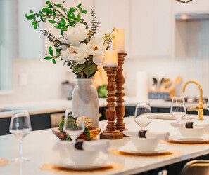 A dining table set with white tableware, a vase with white flowers, and a candle. - Spacious, Immaculate 4350 sq ft Home• Amazing Kitchen (Coeur d'Alene)