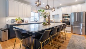 A modern kitchen with white cabinets, stainless steel appliances, and a central island with bar stools. - Spacious, Immaculate 4350 sq ft Home• Amazing Kitchen (Coeur d'Alene)