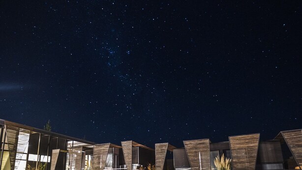 A series of modern, wooden-roofed cabins under a starry night sky. - Taka Matanzas (Navidad)