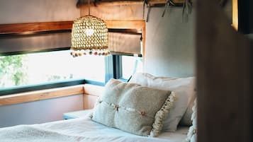 Un dormitorio acogedor con cama, lámpara colgante y ventana con vistas a follaje.