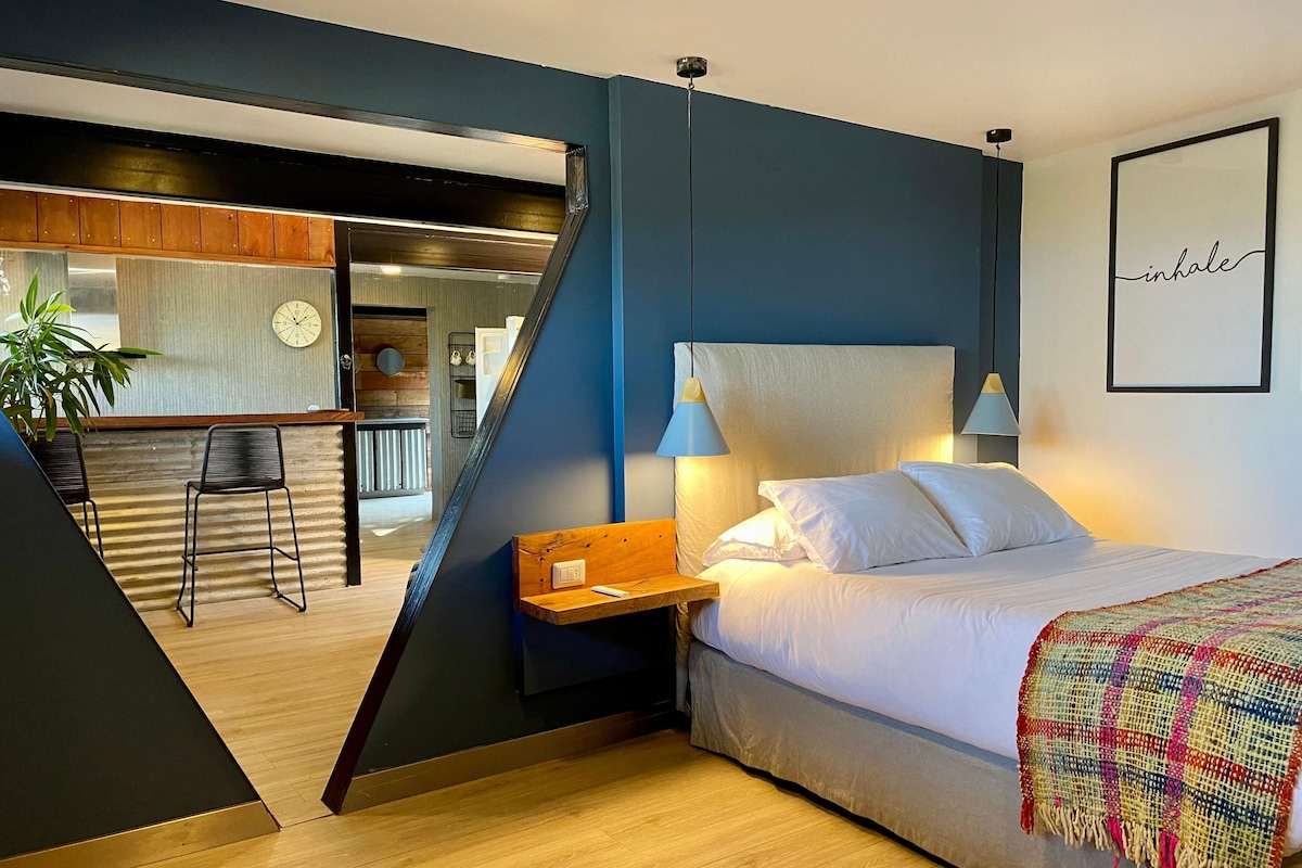 A modern bedroom with a bed, bedside table, and a colorful throw blanket.