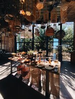Un comedor con diferentes lámparas colgantes y una mesa de buffet con comida y bebidas.