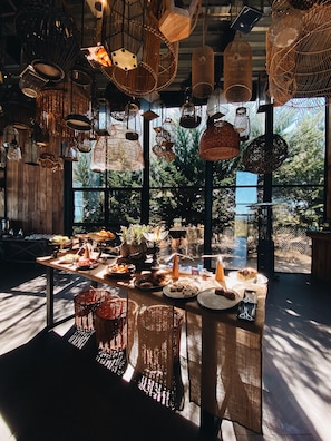 A dining area with a variety of hanging light fixtures and a buffet table with food and drinks. - Taka Matanzas (Navidad)