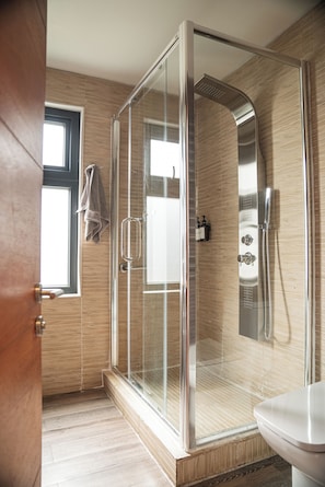 A modern bathroom with a glass-enclosed shower, a toilet, and a window. - Taka Matanzas (Navidad)