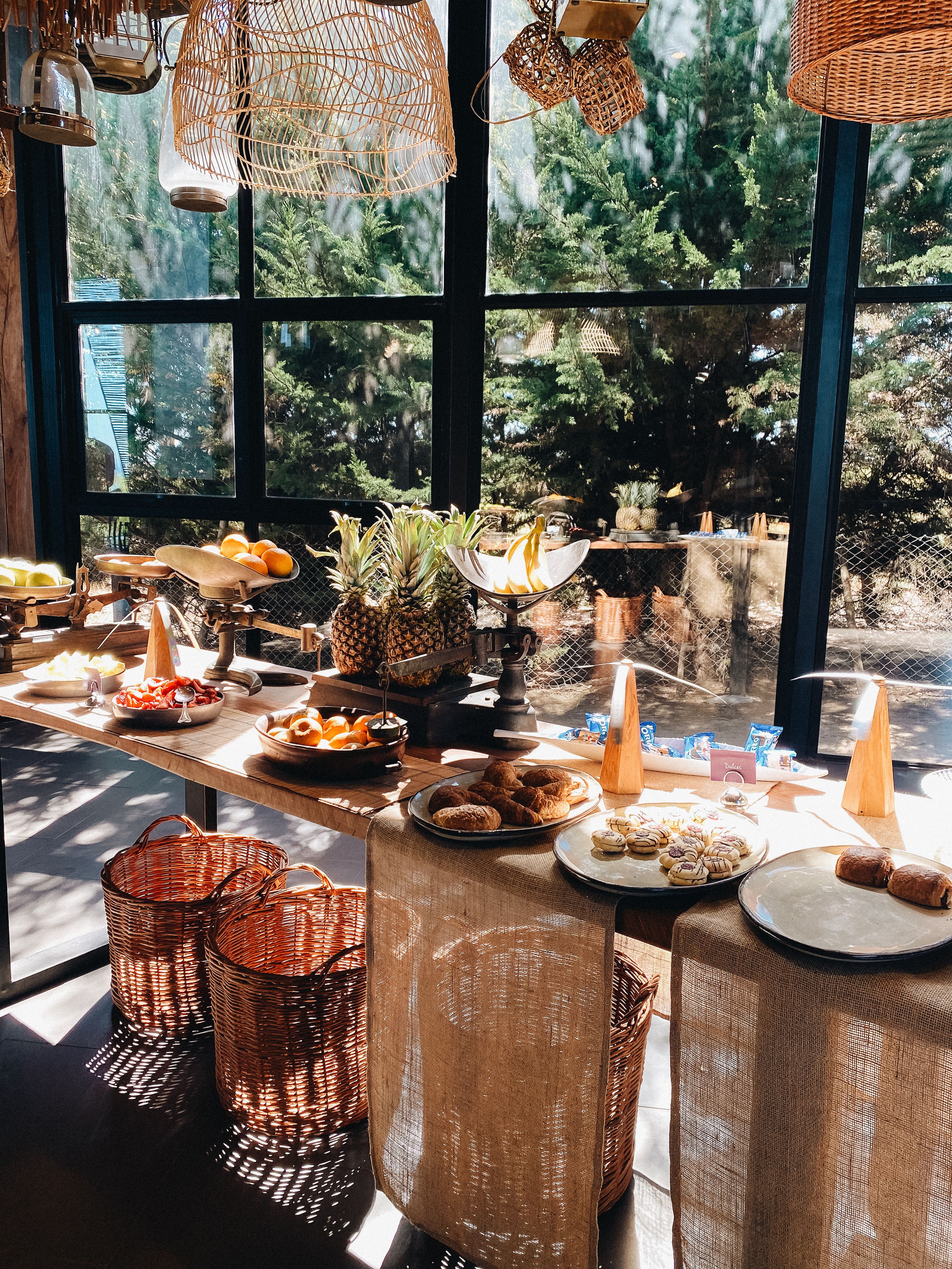 Un bufé de desayuno con diversas opciones de comida y cestas de mimbre.