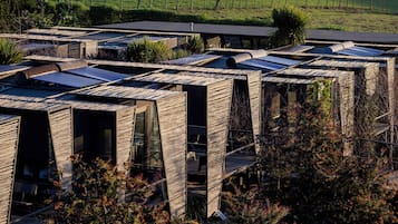 Un edificio moderno con una fachada de madera distintiva, paneles solares y vista al océano.