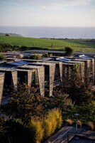 Un edificio moderno con una fachada de madera distintiva, paneles solares y vista al océano.