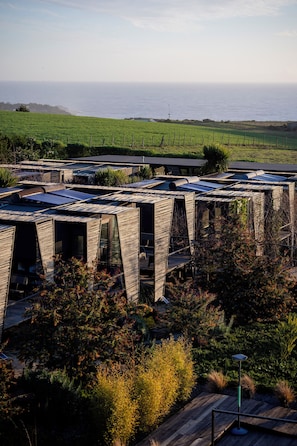 A modern building with a unique wooden facade, solar panels, and a view of the ocean. - Taka Matanzas (Navidad)