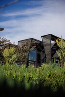 A modern building with a unique geometric design, surrounded by lush greenery.