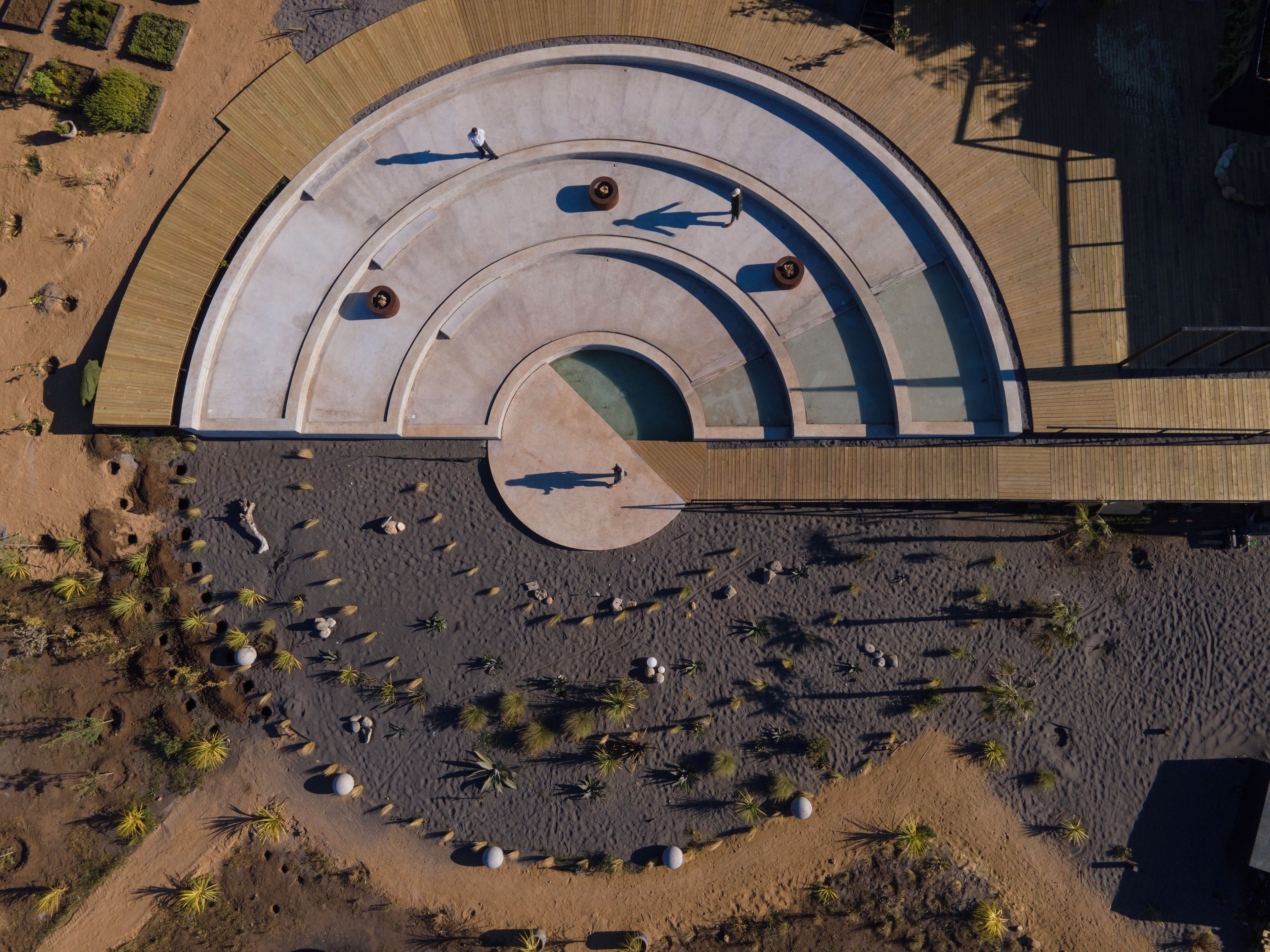 An aerial view of a circular plaza with concentric seating areas and palm trees.