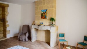 Una habitación con pared de piedra, un escritorio con planta, dos sillas y una alfombra estampada.
