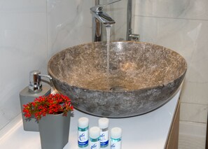 A bathroom with a large stone sink, a modern faucet, and a small potted plant with red flowers. - Anastasia & Marie luxury & traditional residence with large jacuzzi 1 minute sea (Κίσσαμος)