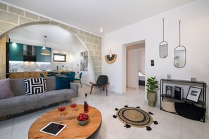A modern living room with a sofa, coffee table, and a dining area with a kitchen in the background.
