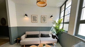 Una sala acogedora con un sofá, dos mesitas auxiliares y una lámpara colgante.
